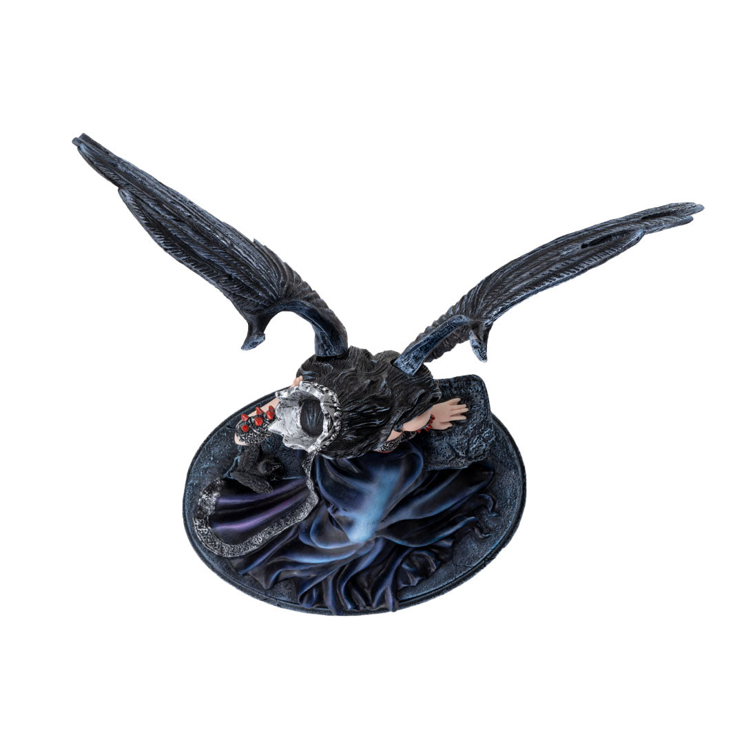 Fairy figurine, black feathered wings and hair, she wears a crown, pale skin, black and blue dress, sitting on a wall with a raven. Shown top down