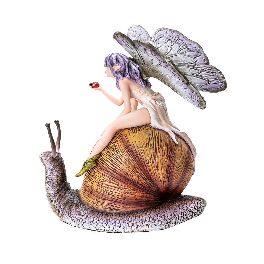 Figurine of a fairy with purple-gray wings and hair, cream colored dress, holding a ladybug and riding a snail