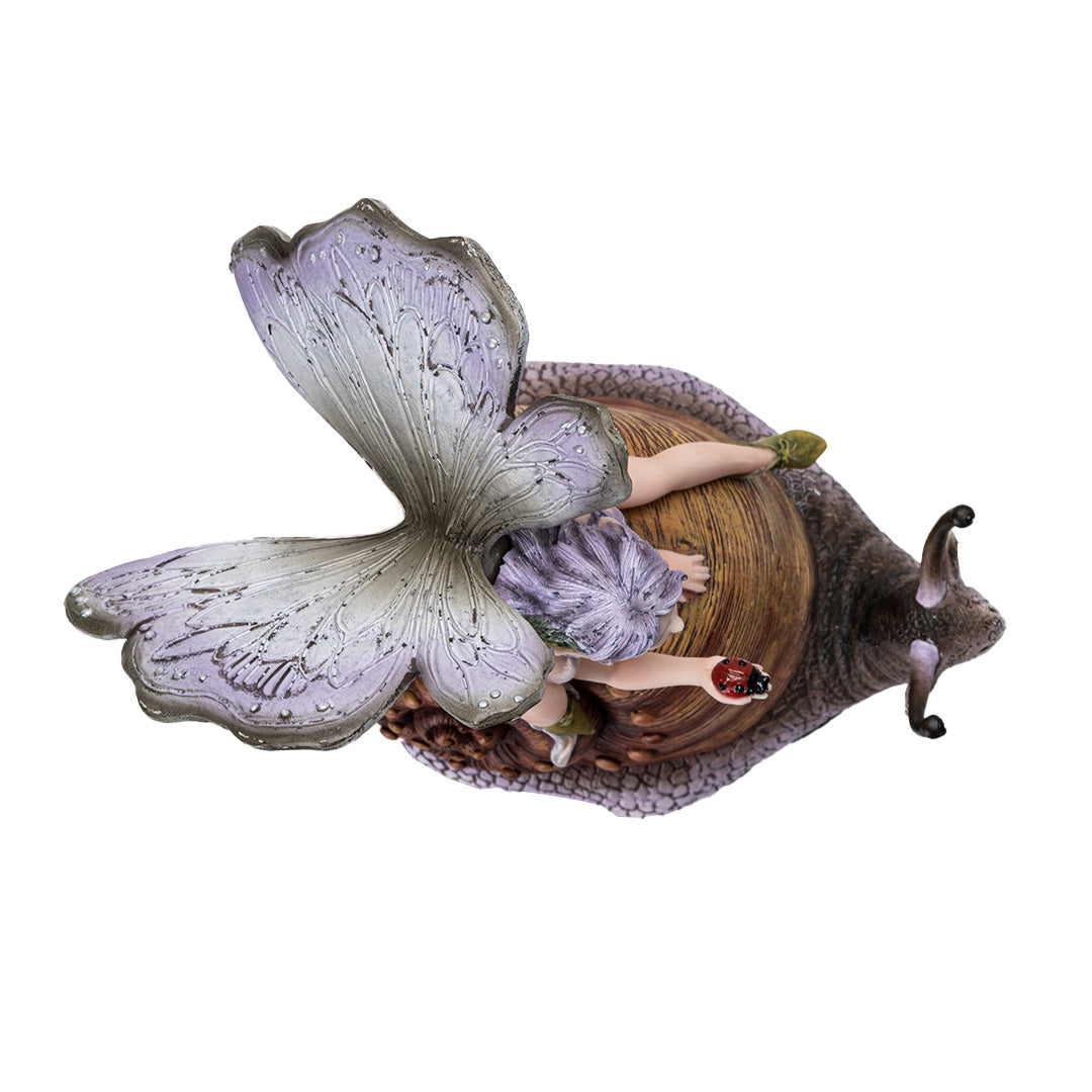 Figurine of a fairy with purple-gray wings and hair, cream colored dress, holding a ladybug and riding a snail, shown top down