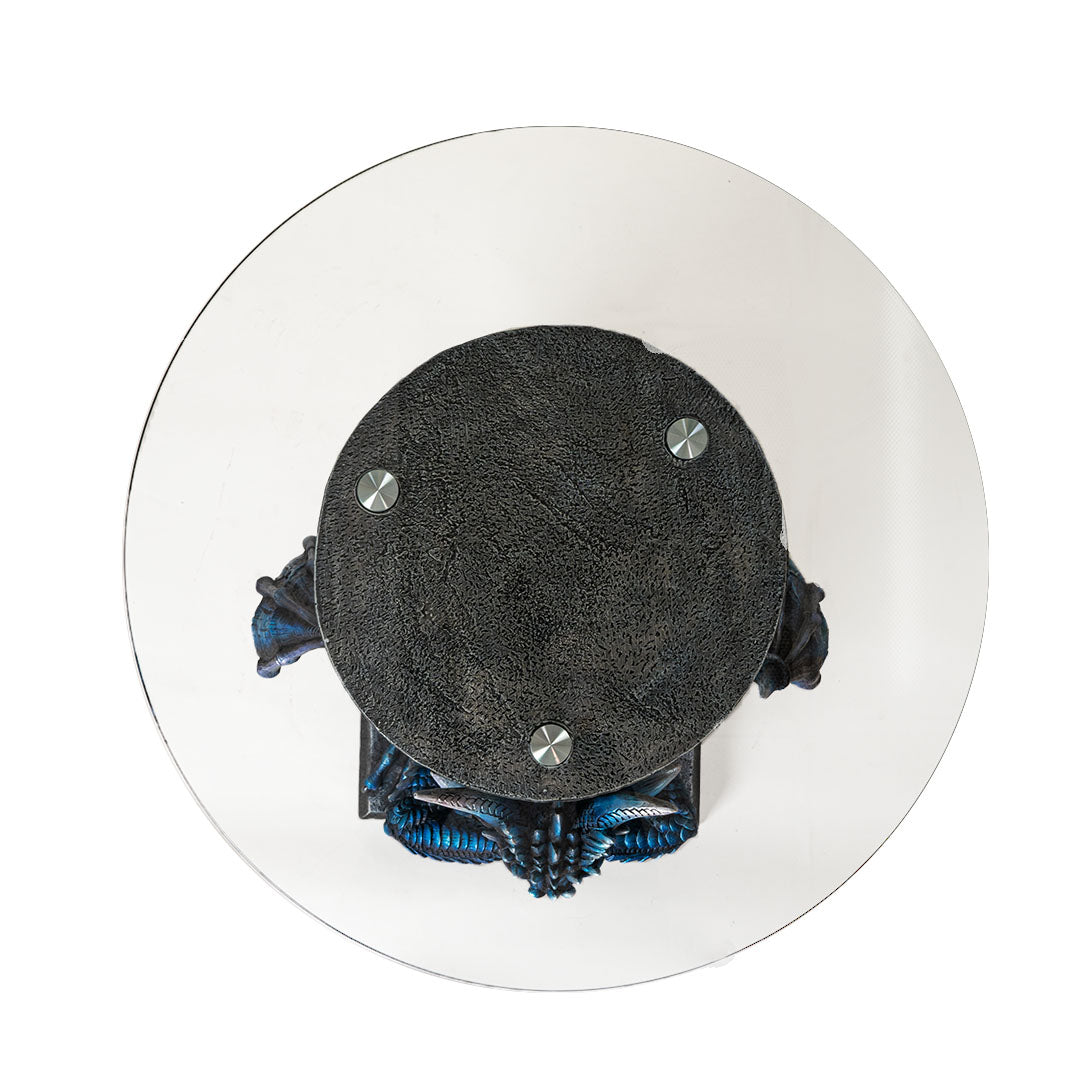 Glass topped table. Base is a blue dragon with spread wings holding a sword. Shown from above, looking at glass top