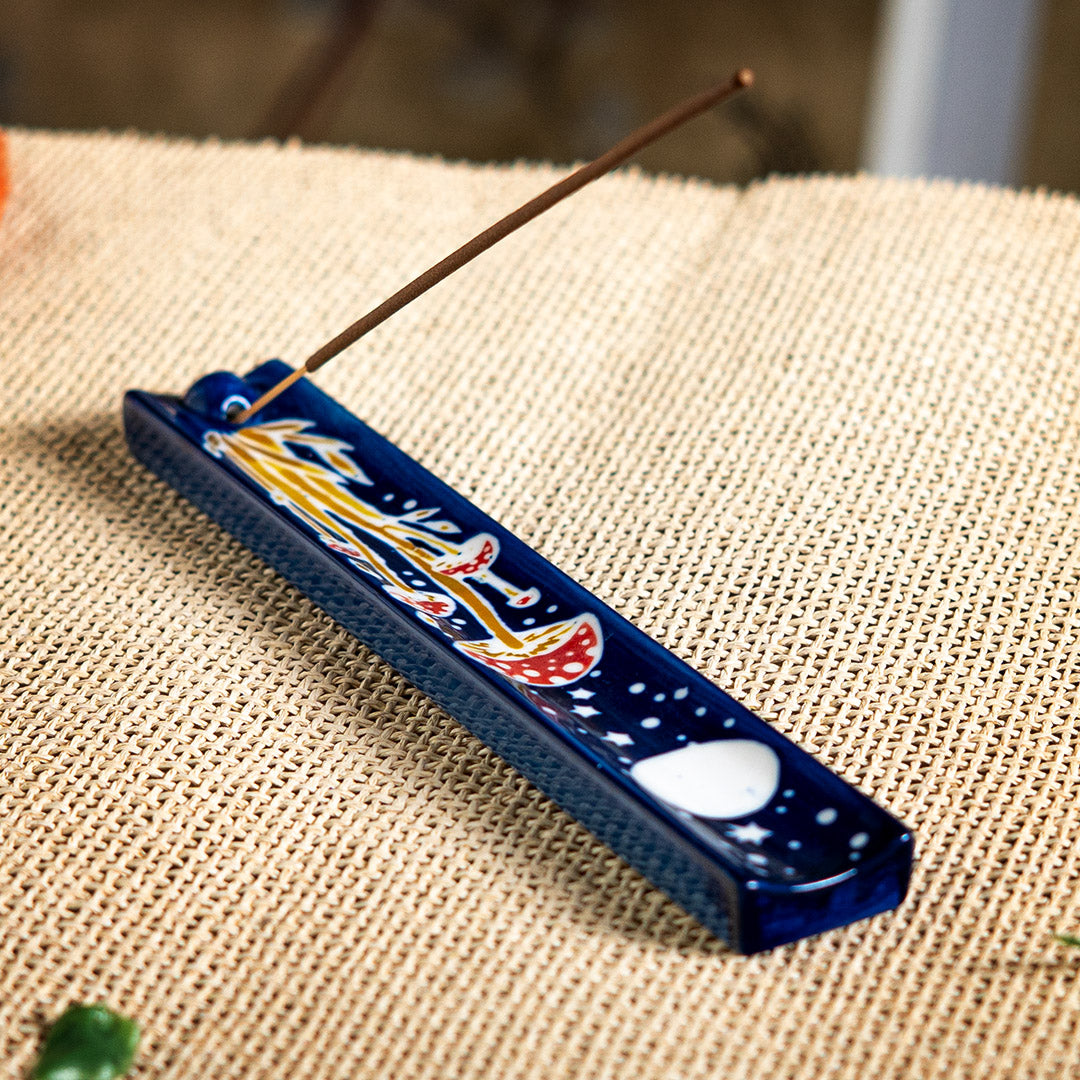 Blue ceramic incense holder with red and white mushrooms painted on under a full moon