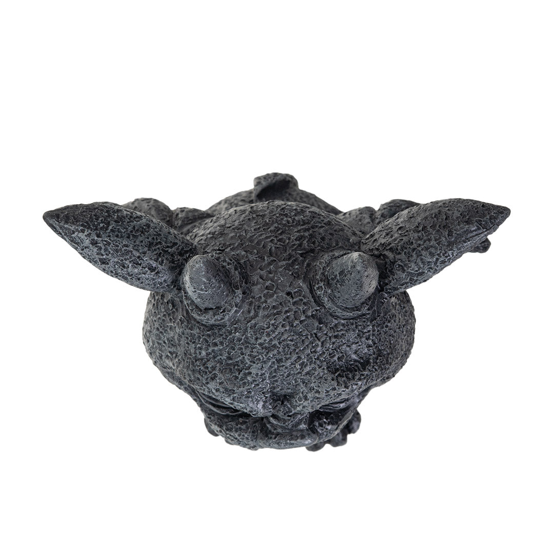 Statue of a gargoyle creature with large eyes, horns and wings in faux-stone finish, shown top down