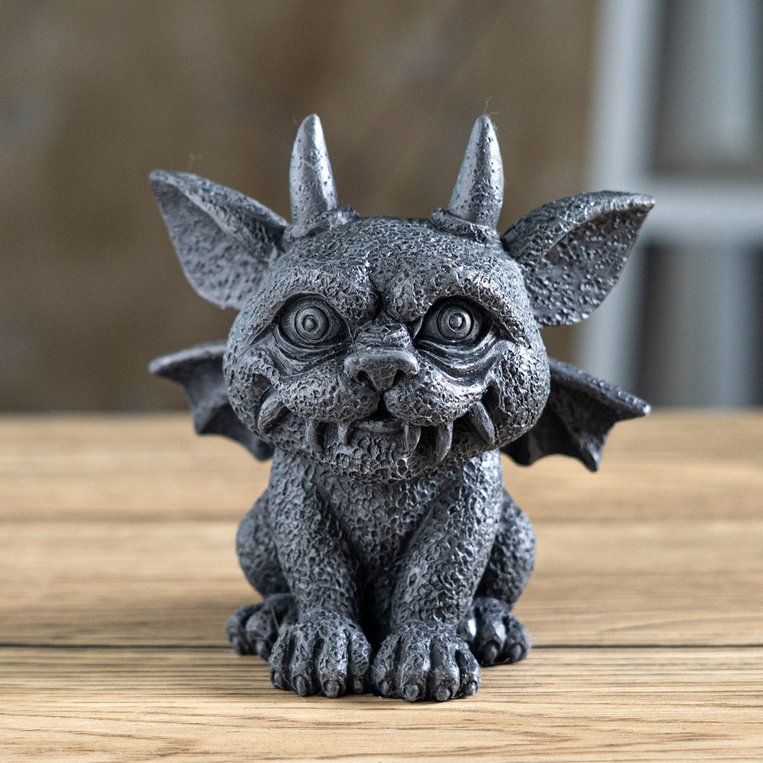 Statue of a gargoyle creature with large eyes, horns and wings in faux-stone finish