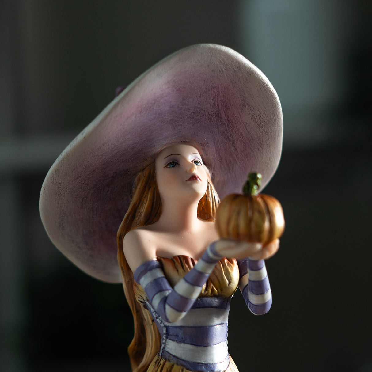 Closeup of witch in purple holding up a pumpkin