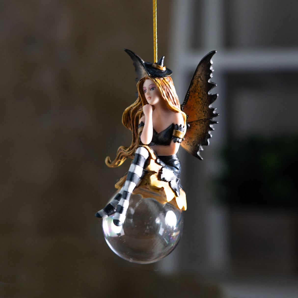 Fairy ornament with witch-themed attire perched on a glass bubble