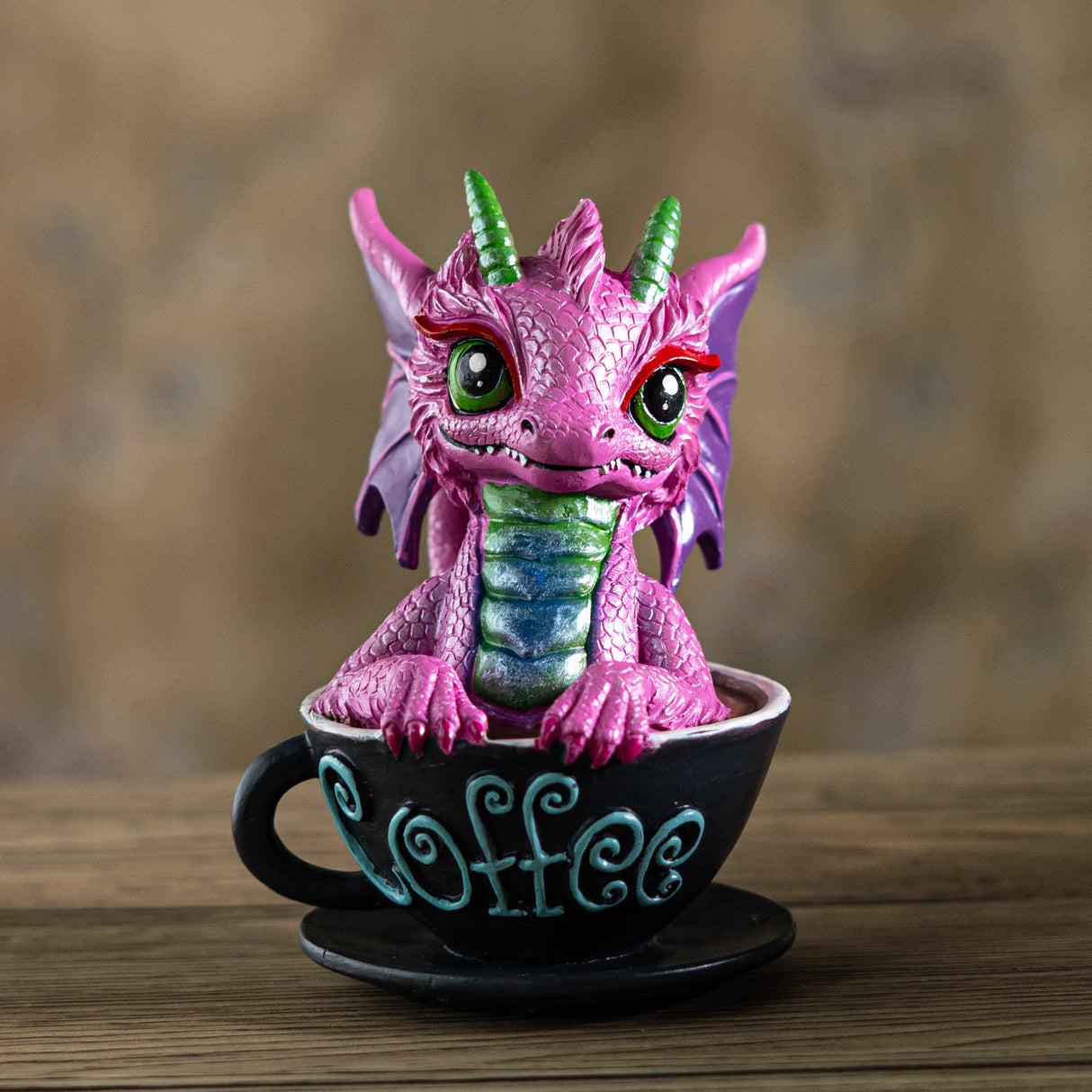 Pink dragon figurine inside a black coffee cup with 'Coffee' written on it