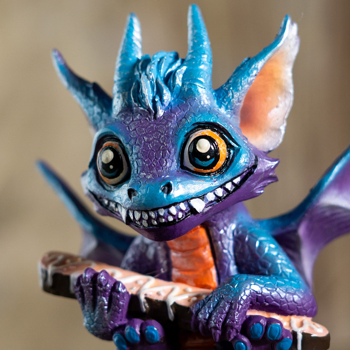 Colorful dragon figurine with blue, purple, and orange colors, holding a biscotti
