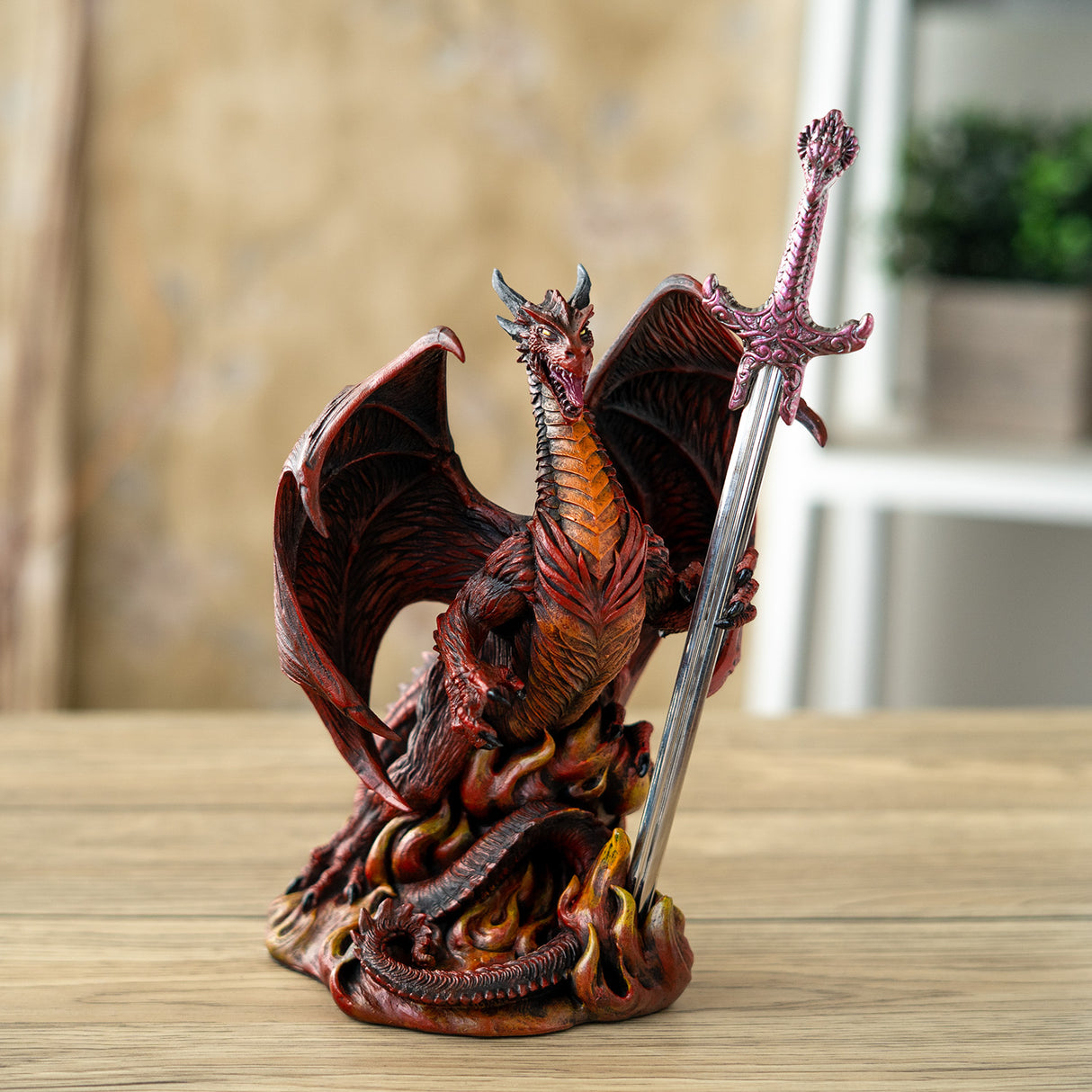 Red and orange dragon figurine holding a sword letter opener amidst flames