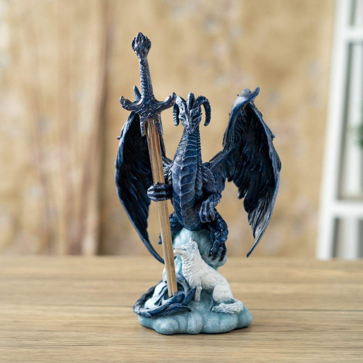 Blue dragon figurine holding a sword letter opener with a white wolf at its feet