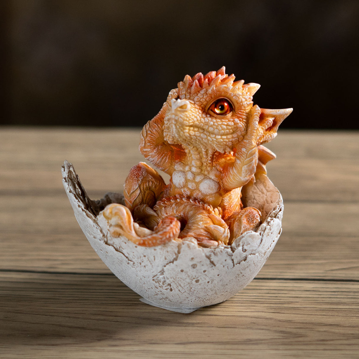 Small orange dragon figurine emerging from a cracked eggshell