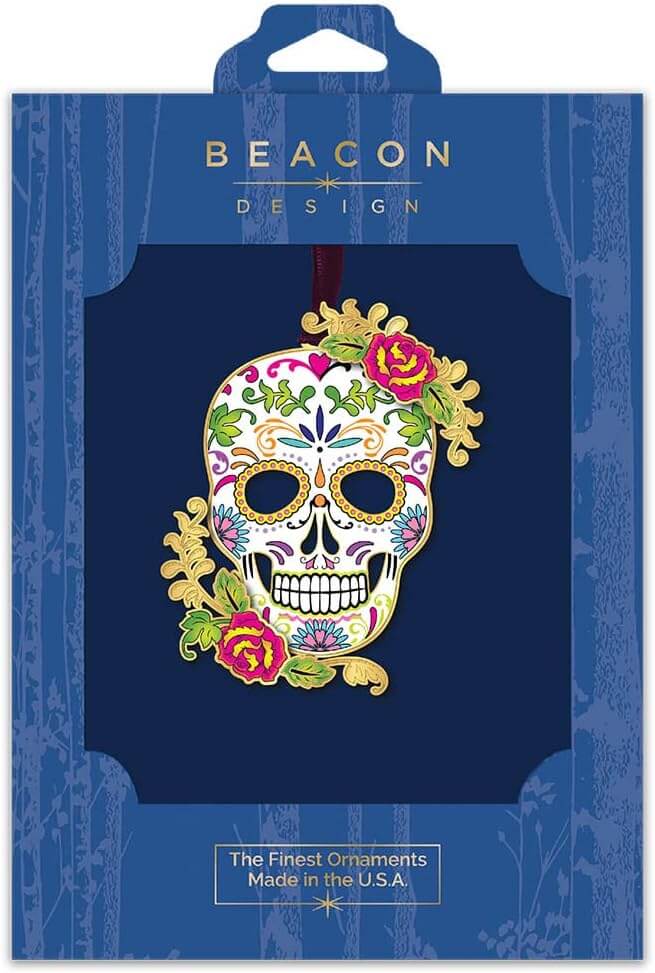 Colorful sugar skull skeleton ornament with red flowers and swirl designs and leaves, shown boxed