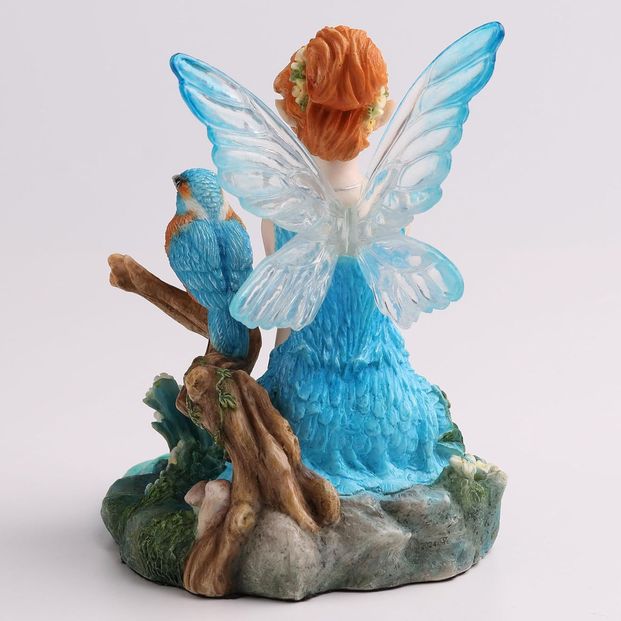 Figurine of fairy in blue dress with matching wings and red hair sitting by pond with kingfisher bird, shown from the back