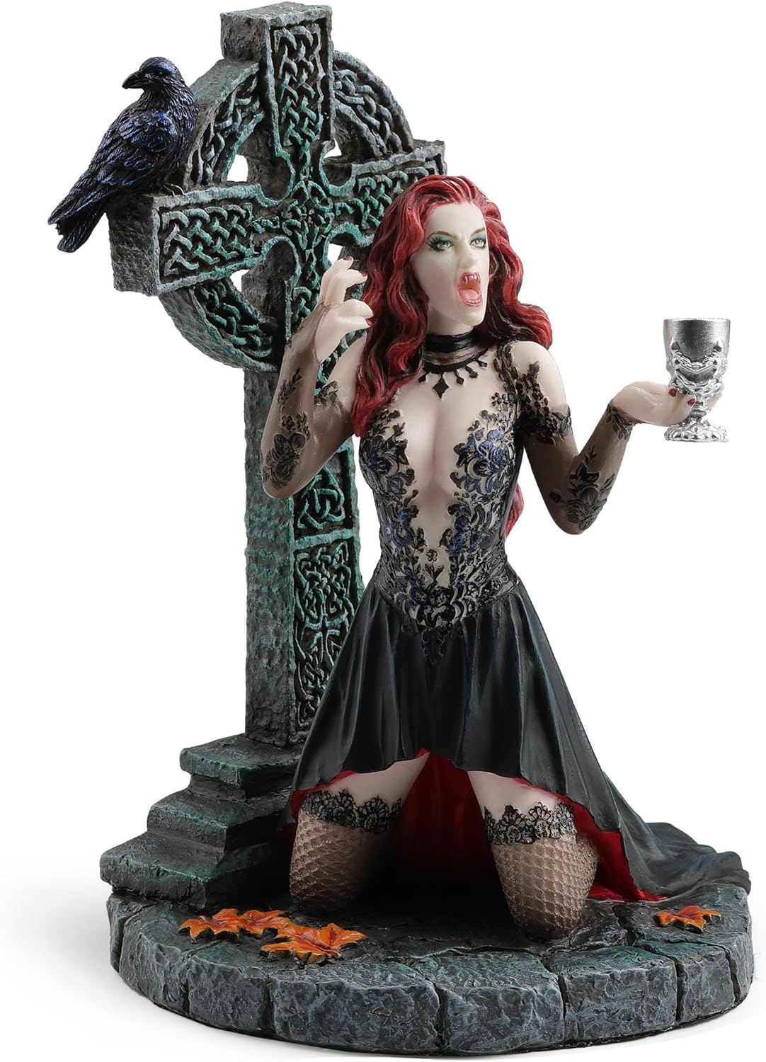 Gothic figurine of a vampire woman with red hair holding a goblet in front of a Celtic cross with a raven perched upon it