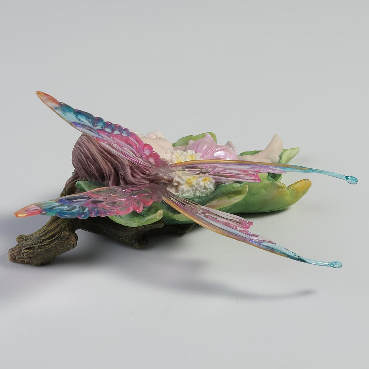 Fairy figurine with colorful wings, cuddling a bunny on a leaf