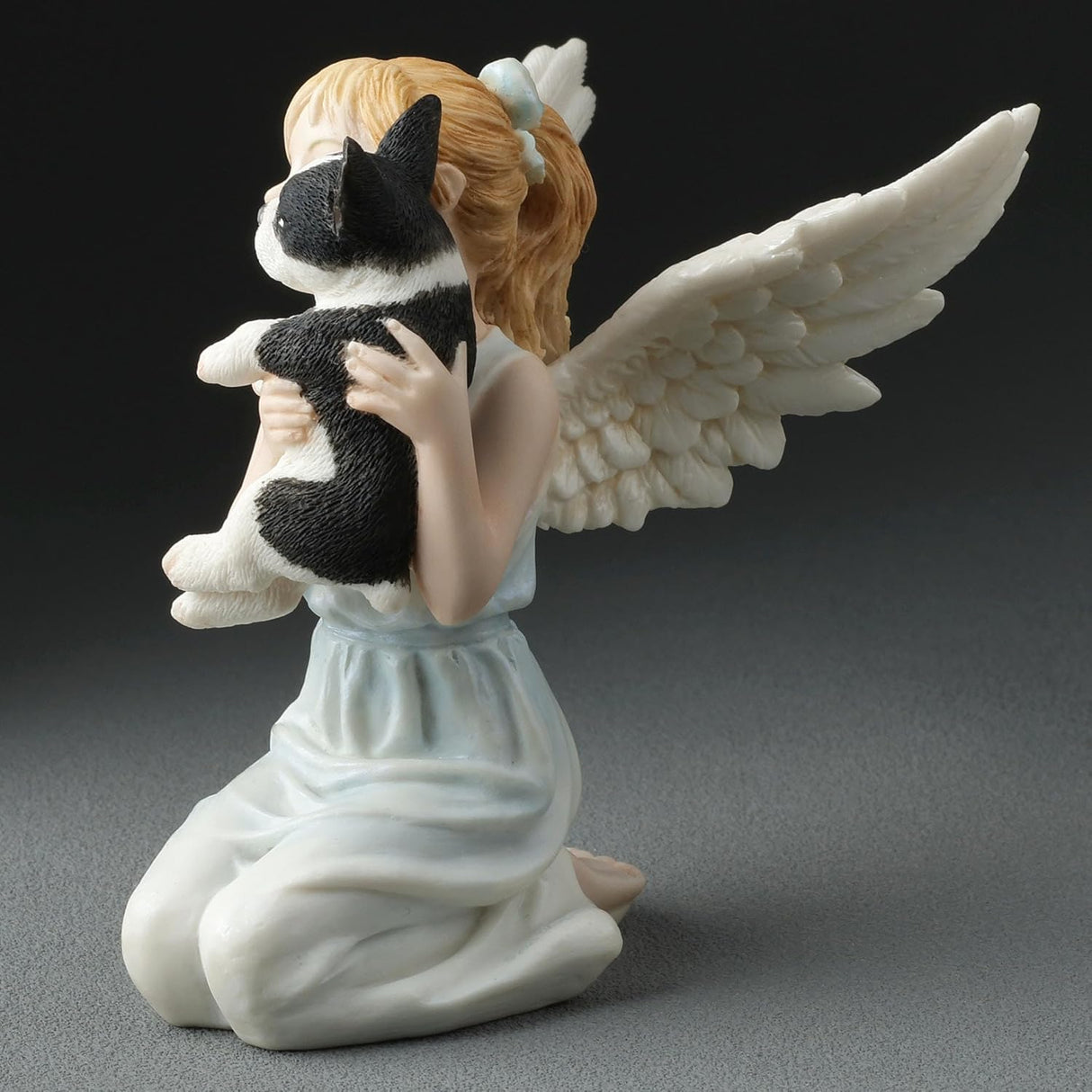 Angel figurine holding a small French Bulldog, shown from the side