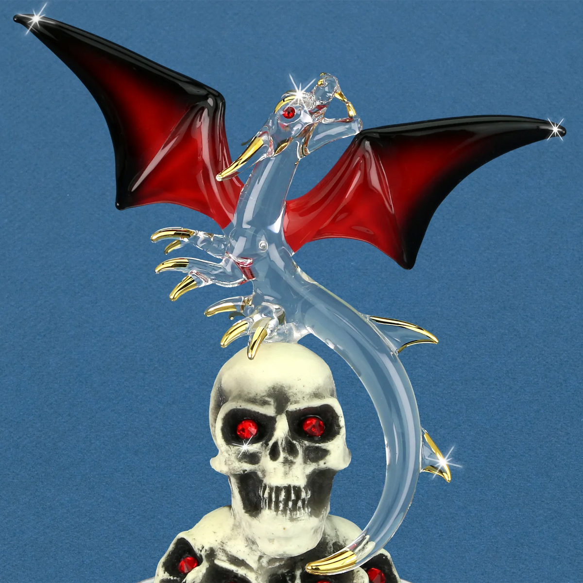 Closeup of glass red and black winged dragon with gold accents on stack of three red-eyed skulls