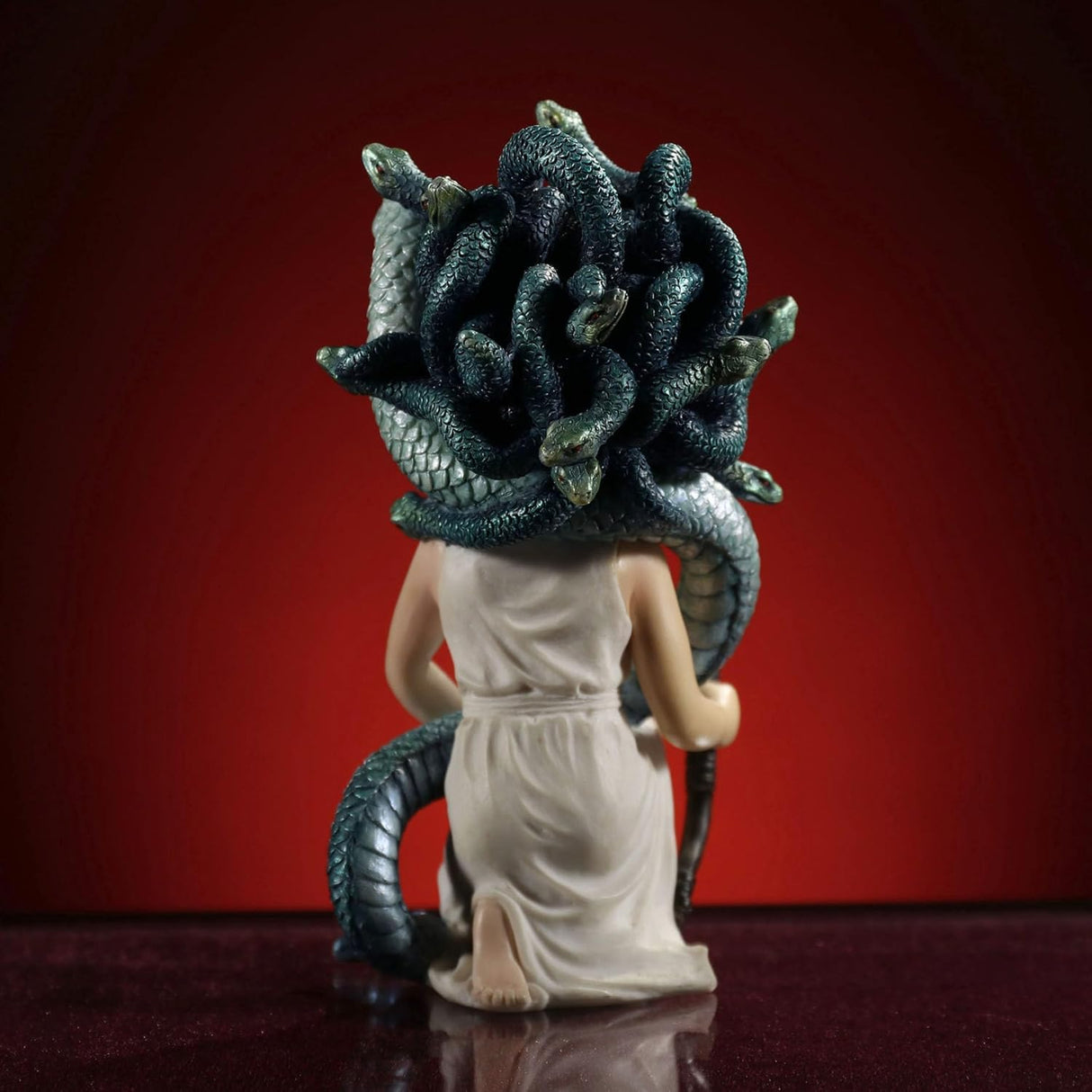 Figurine of Greek myth Medusa, woman with snakes for hair, holding a bow, shown from the back