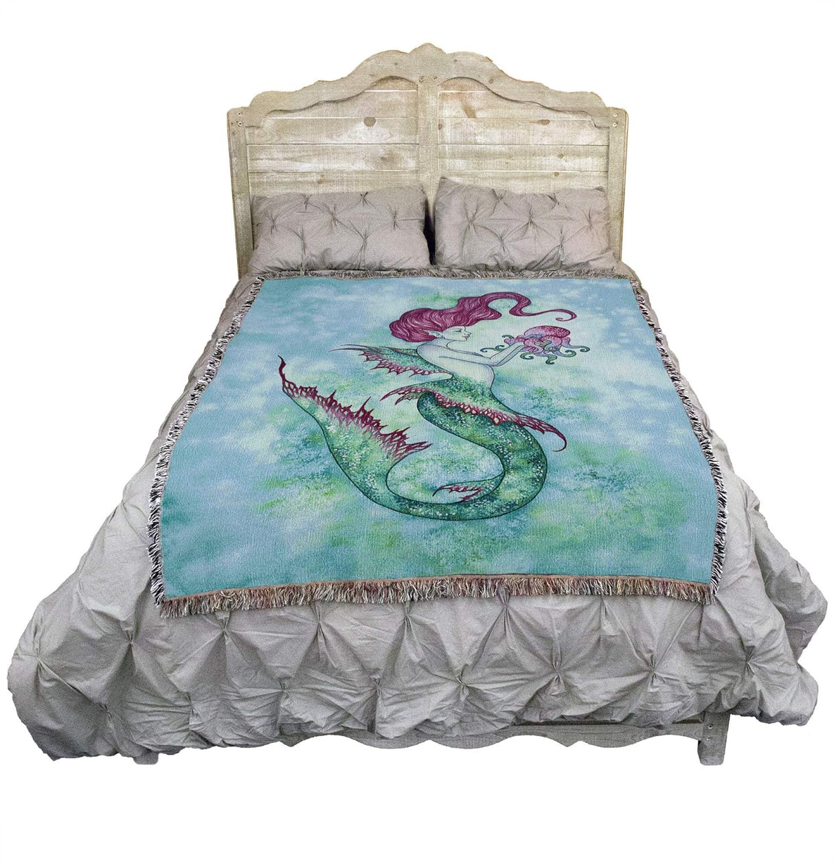 Tapestry blanket, pink haired mermaid holding matching octopus friend. Aqua green tail and scales, on a watery blue backdrop. Shown on a bed