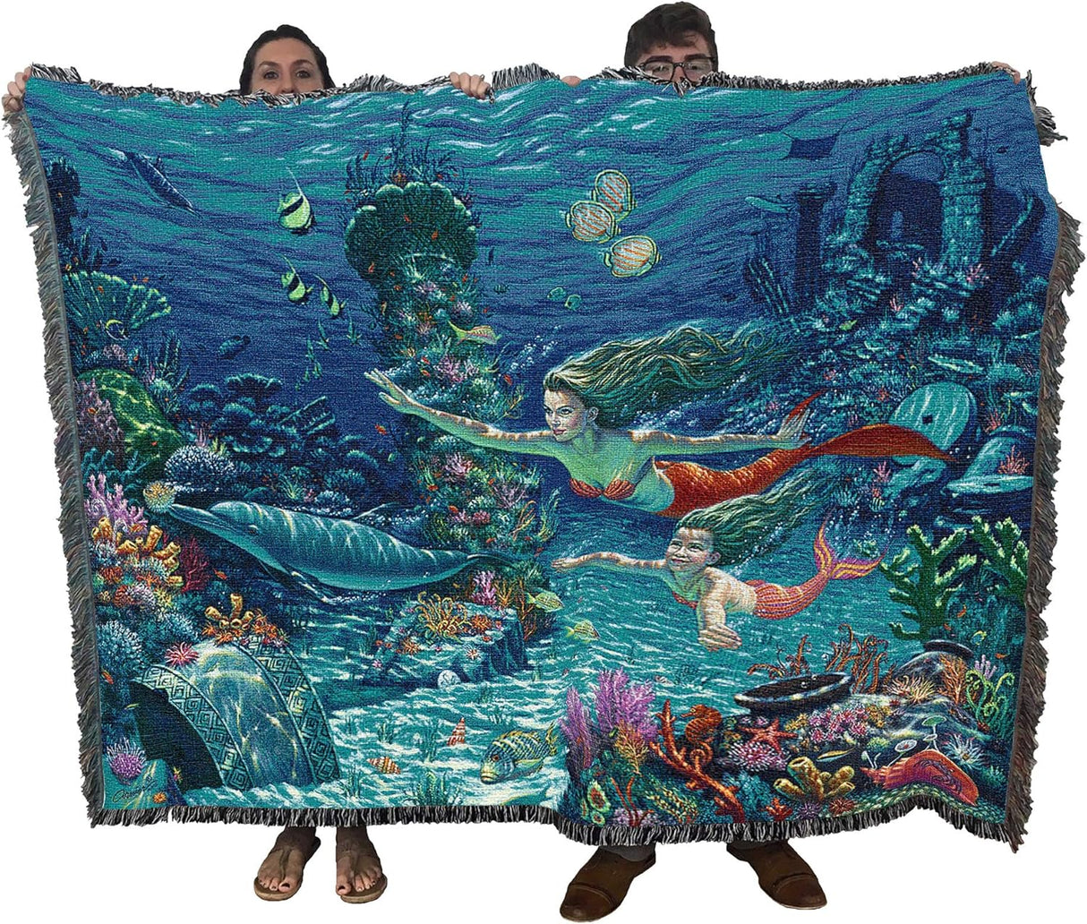 Blanket with mermaid design held by two people, featuring underwater scene with mermaids and fish.