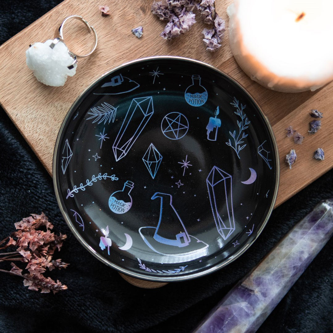Round trinket dish with witchy designs of hat, crystals, plants, candles in gradient blue purple on black background