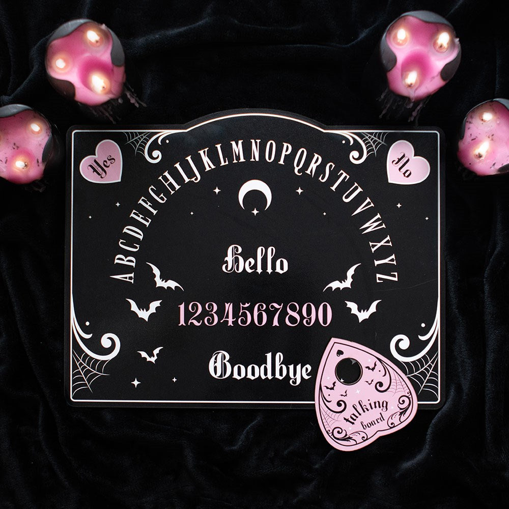 Talking board with pink hearts, bats, and planchette on a white background