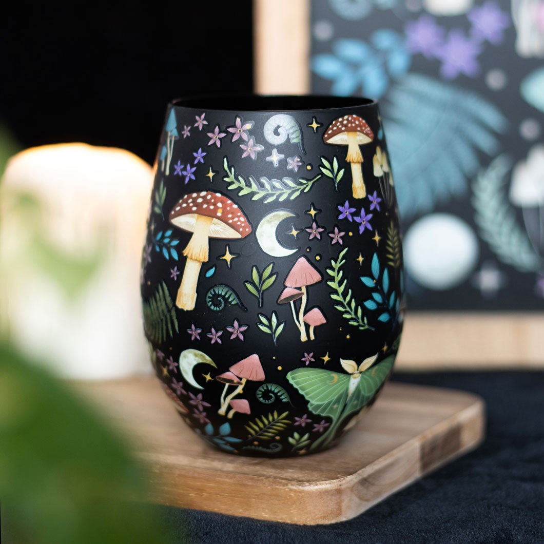 Stemless wineglass with all over patterns on black of mushrooms, ferns, luna moth, moon and stars, flowers