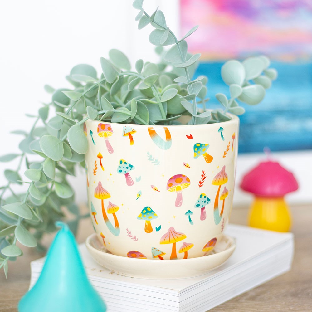 Plant pot with saucer. White base with colorful fungi and mushrooms pattern. shown with plant in it