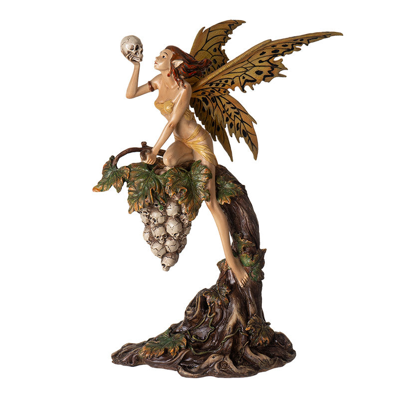 Figurine of fairy in tan garb with tan and black wings holding skull, perched on grapevine of more skulls