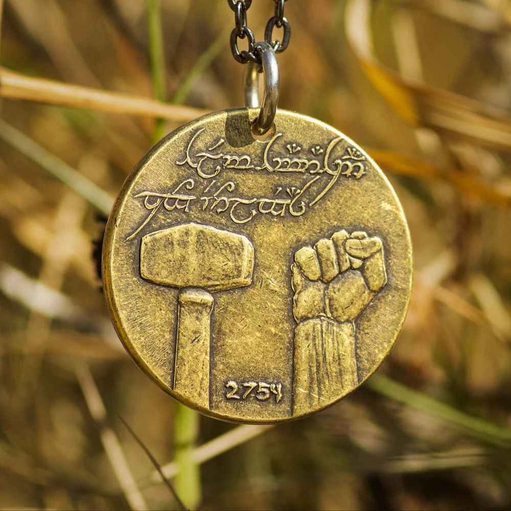 Brass pendant with hammer and fist design on a grassy background and elvish runes, Lord of the Rings