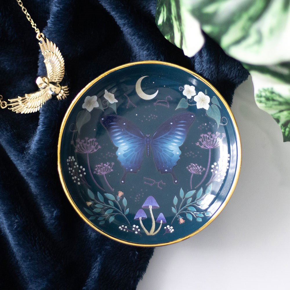 Round trinket dish, teal background with gold edging, designs of crescent moon, flowers, blue moth, mushrooms