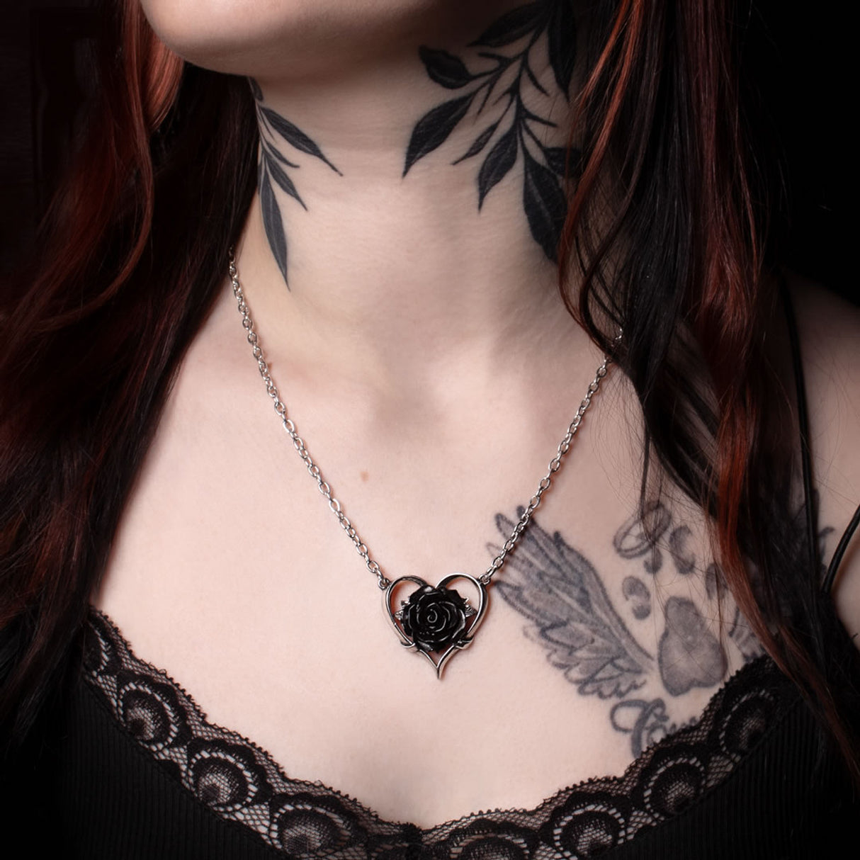 Pewter heart pendant with black rose on a chain, shown worn