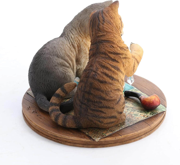 Orange tabby and grey cat contemplate a crystal while sitting on a map with magnifying glass & pipe nearby. Figurine based on artwork of Lisa Parker. Shown from the back