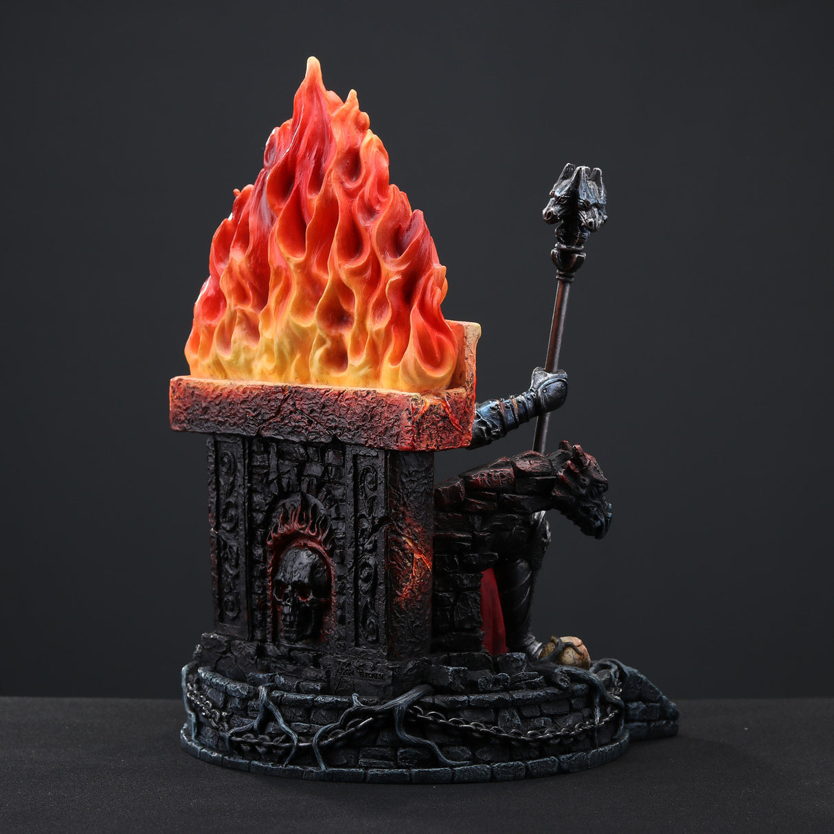 Figurine of skeleton in armor and crown holding staff, sitting on fiery throne with gargoyles, piles of human skulls, shown from the back