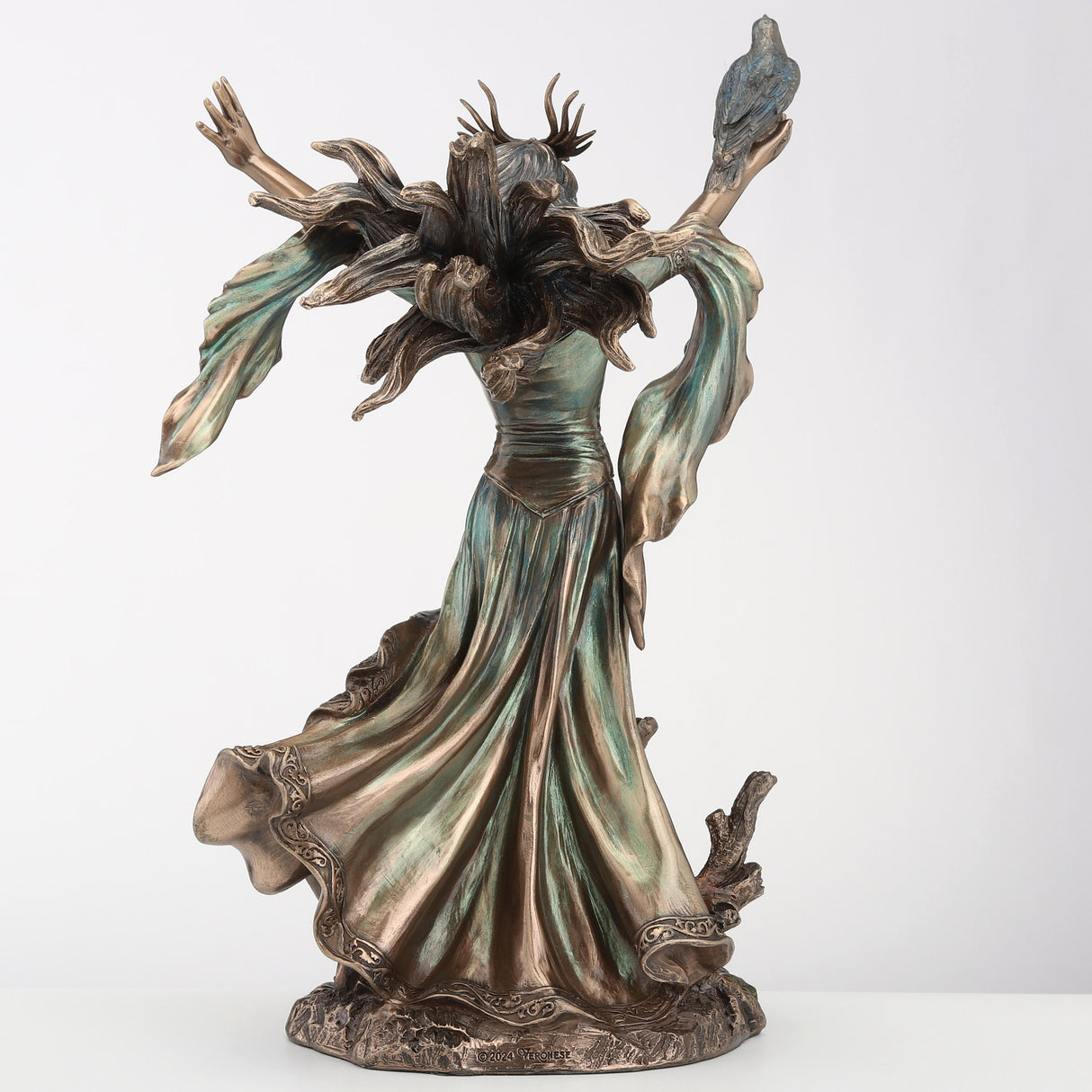 Figurine of the sorceress Morgan le Fey from Arthurian legend. Bronze hue with raven on arm, flowing dress and hair, shown from the back