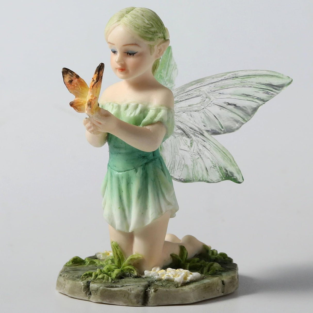 Figurine of fairy in pale green, kneeling with a butterfly