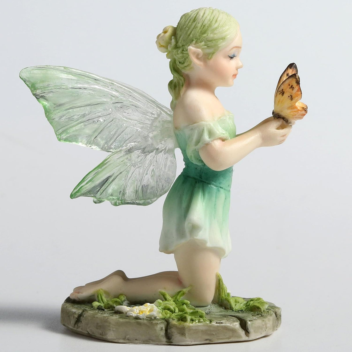 Figurine of fairy in pale green, kneeling with a butterfly
