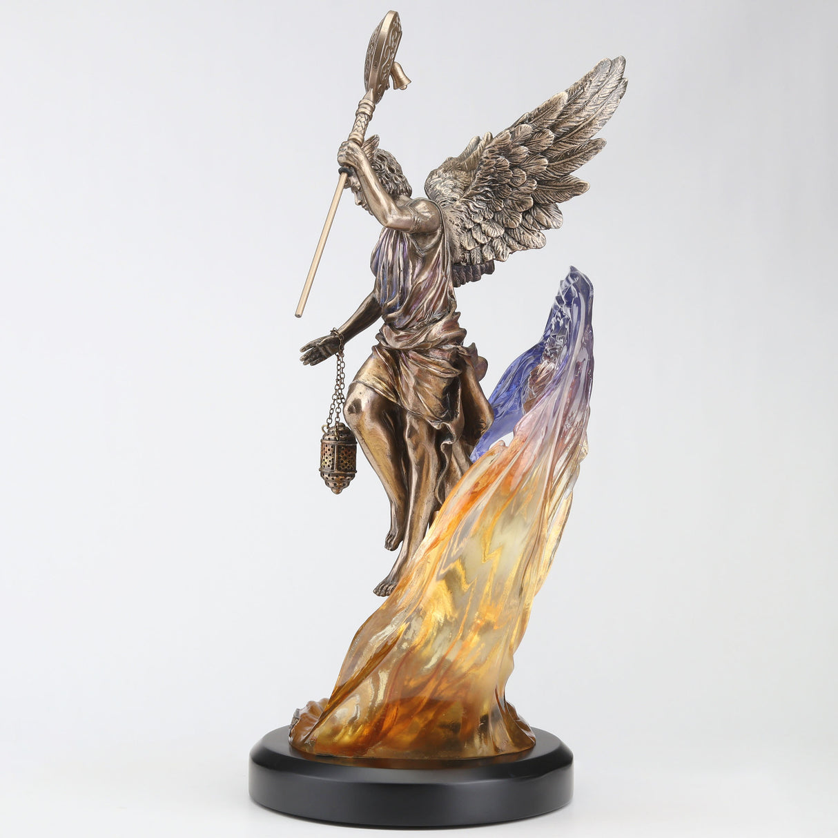 Figurine in bronze hue of Hypnos, Greek god of slumber with lantern and crescent moon staff, feathered wings. Behind him in transparent resin is a purple-yellow-orange cloud and a village below in cold cast bronze