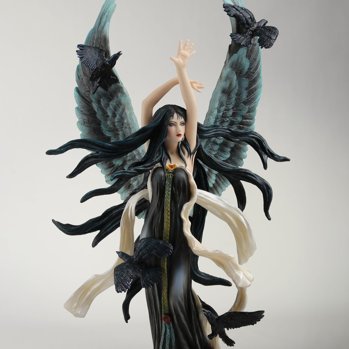 Figurine of fairy with black hair and dress and feathered angel wings, surrounded by ravens