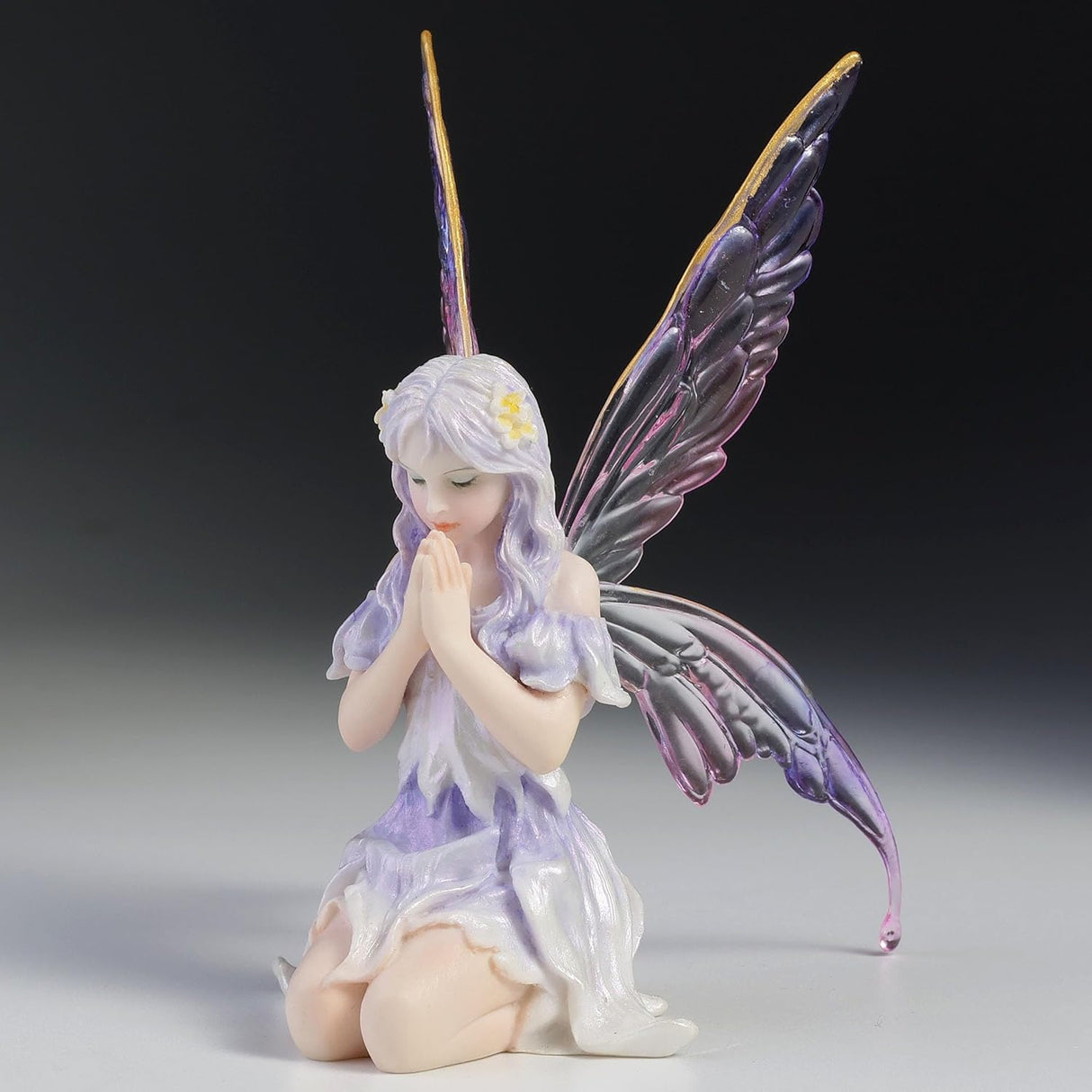 Fairy Figurine, pale purple hair and dress with hands clasped in front of her, eyes closed, transparent wings with shades of purple