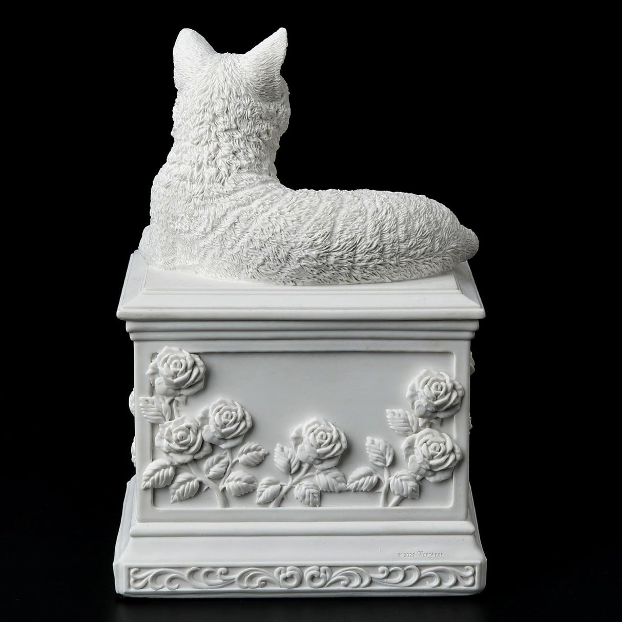 A white cat cremation urn featuring a detailed cat figurine resting on a square pedestal decorated with a central heart-shaped recess and embossed floral rose motifs. Shown from the back