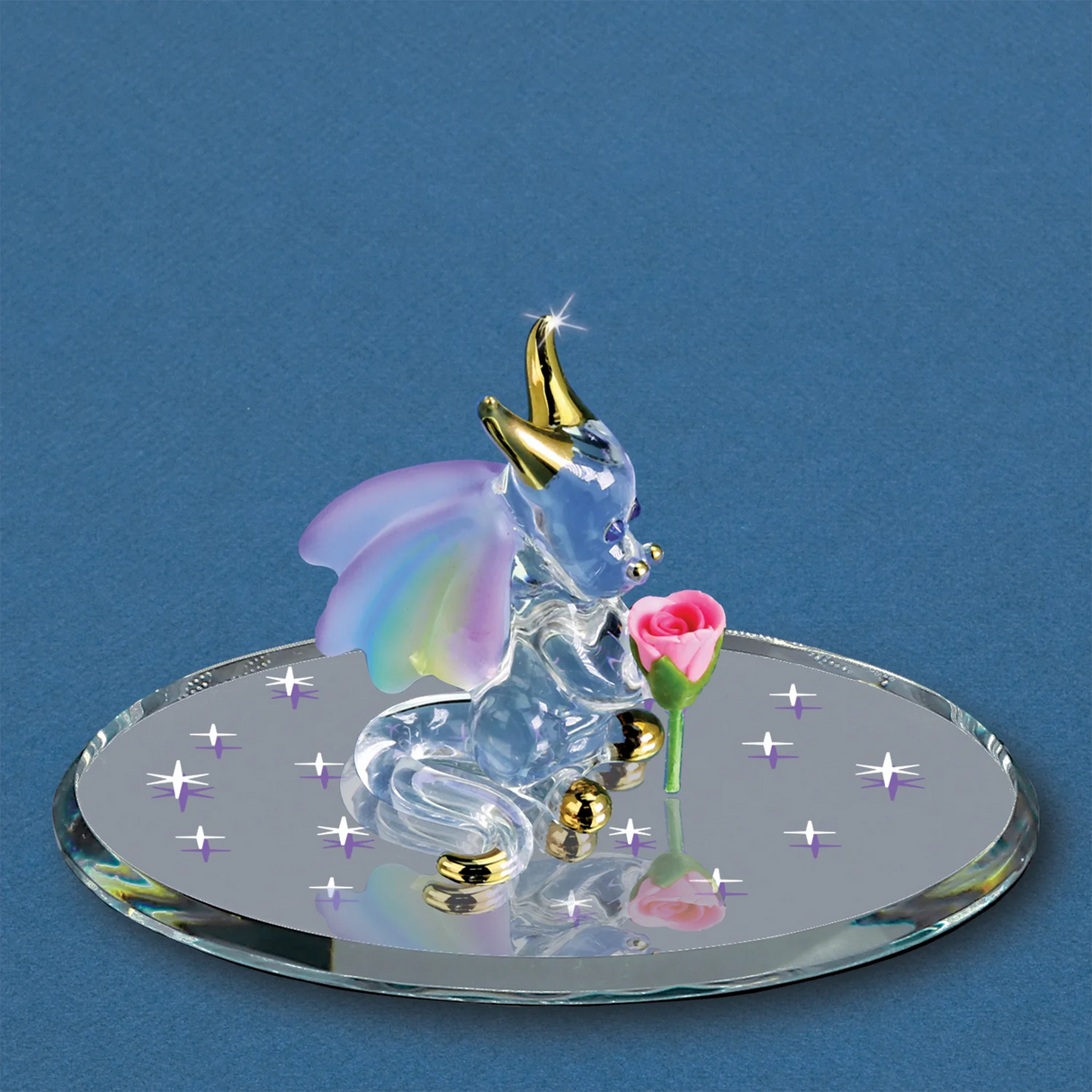 Glass figurine of a baby dragon with rainbow wings on a round base with rose, against a blue background