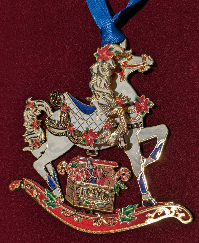 Brass rocking horse ornament with a box of toys, accented in holly and poinsettia