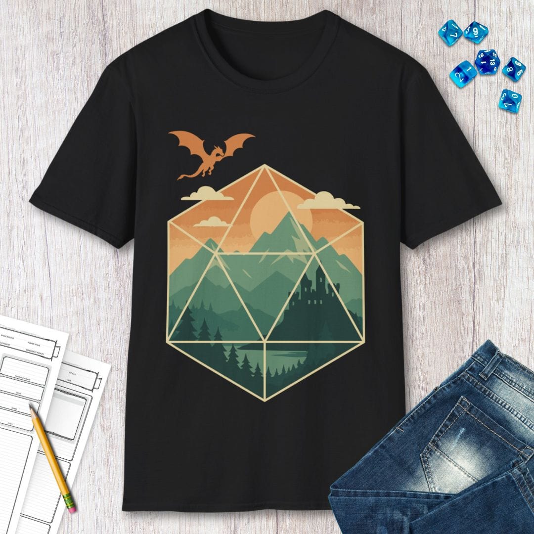 Black t-shirt with a geometric dice landscape design featuring a dragon, mountains, and a castle, shown with dice, papers, jeans