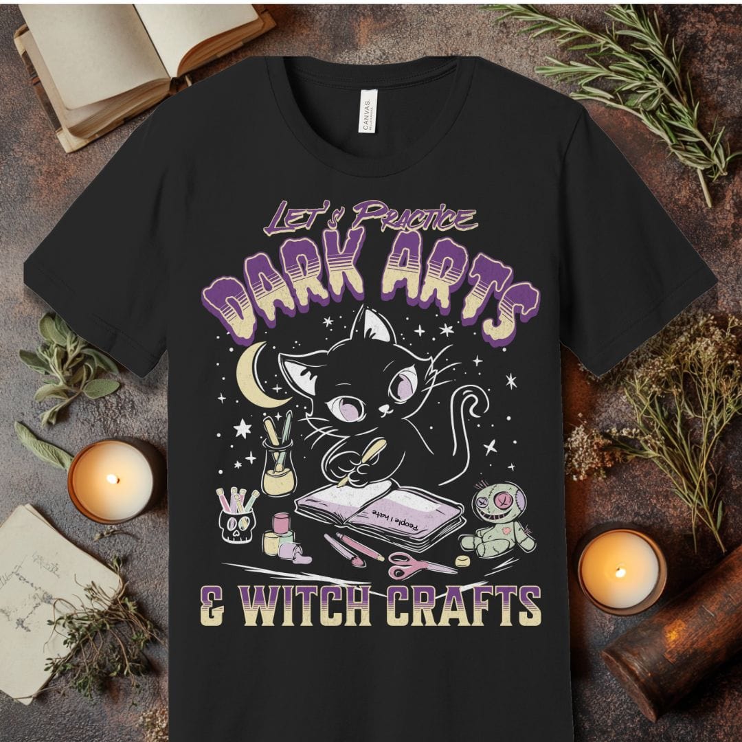Black t-shirt with a cat graphic and text 'Let's Practice Dark Arts & Witch Crafts' on a rustic background.