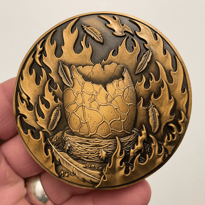 Back of phoenix coin showing egg in nest surrounded by flame