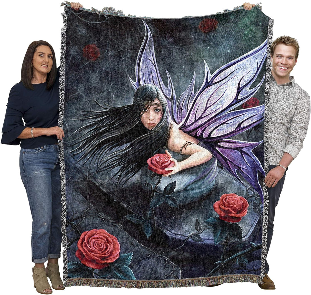Tapestry blanket showing Fairy with purple wings, black hair holding a red rose with thorns on a gravestone. Art by Anne Stokes. Held up by two adults to show large size
