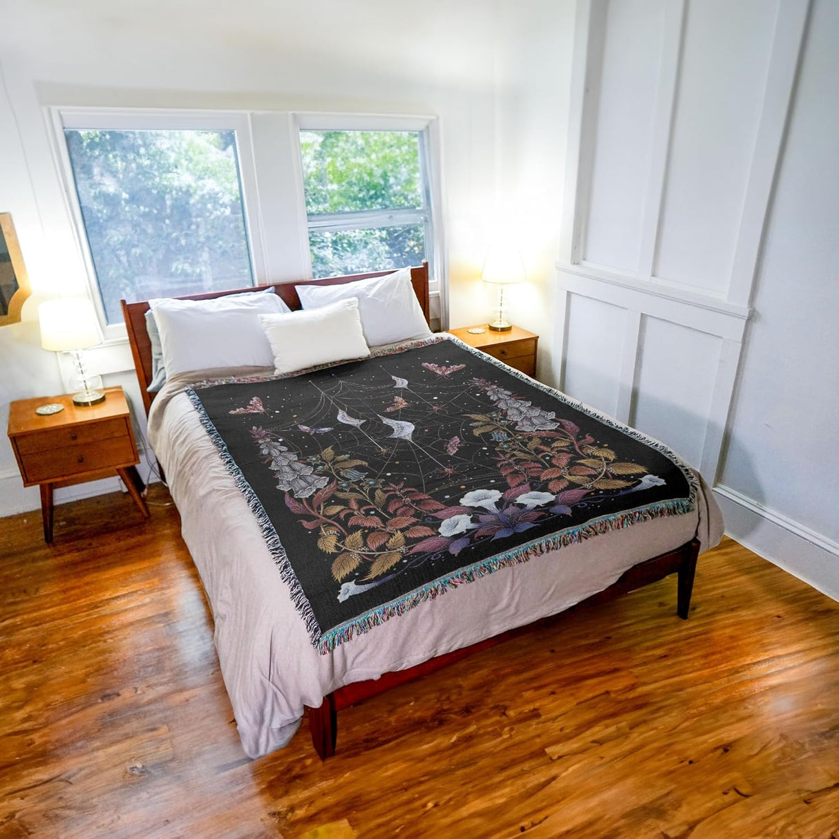 Bedroom with floral-patterned blanket on a bed, wooden floors, and windows.