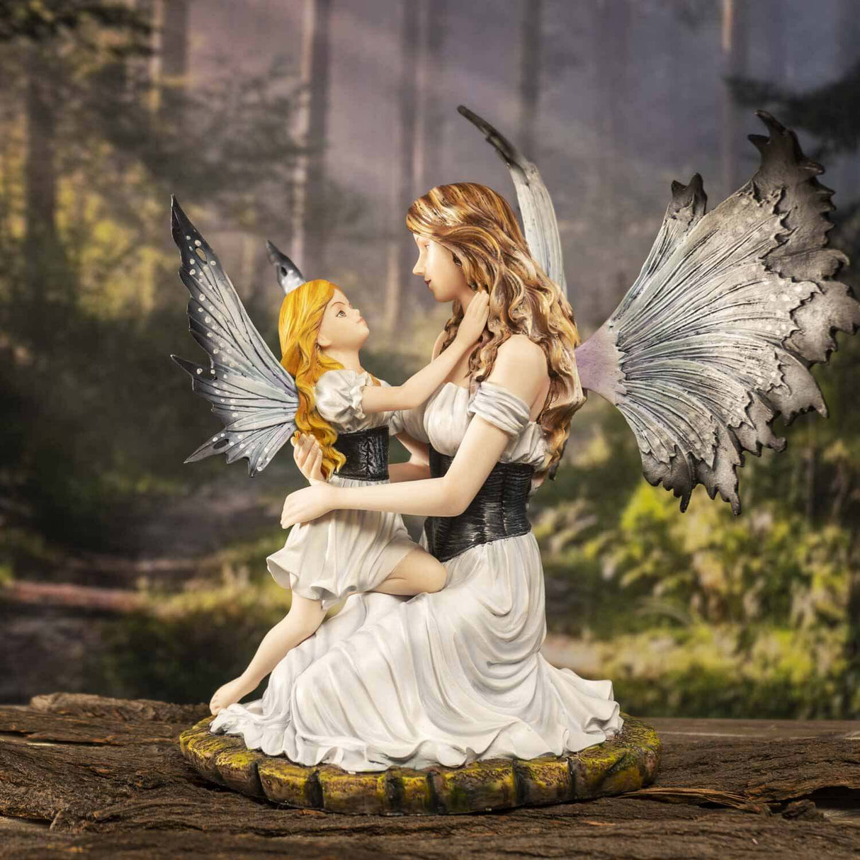 Mother and child fairy figurine in white dresses with blue-grey wings. Shown in a forest setting