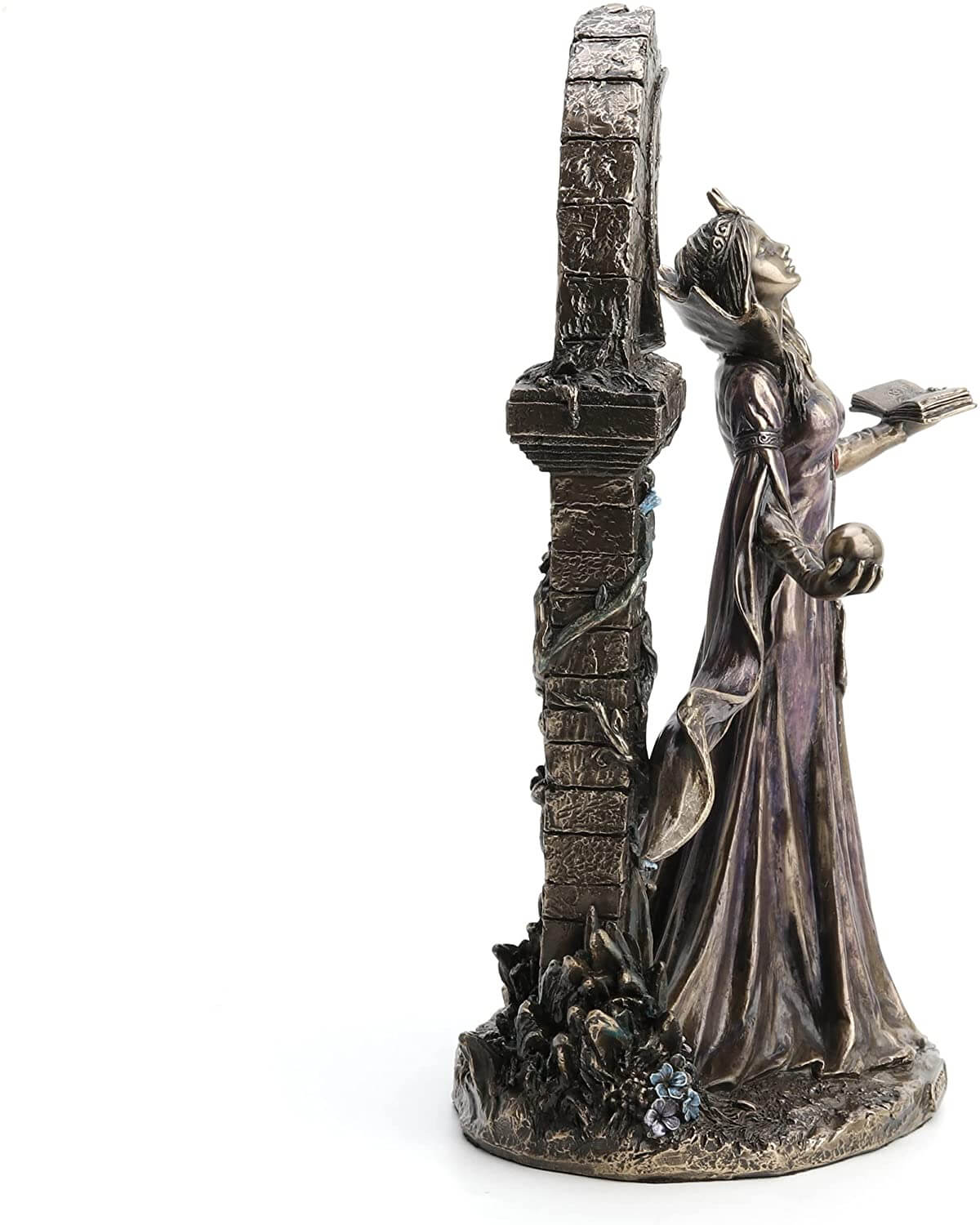 Side view - Aradia s represented standing with eyes closed, face tipped to the heavens. Her dress is long and flowy, and she holds a tome in one hand and an orb in the other. She stands in front of ruins twined with vining flowers.