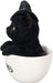 Black kitten in a white teacup. Cat wears a witch hat . Side view